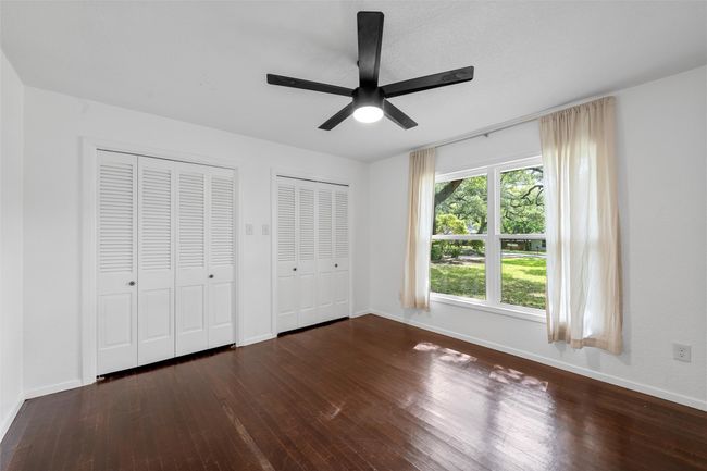 Unfurnished bedroom featuring multiple closets, wood finished floors, baseboards, and ceiling fan | Image 26