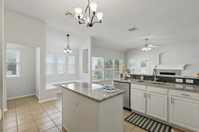 Kitchen with stainless steel dishwasher, a center island, a chandelier, a ceiling fan, and light tile patterned floors | Image 10