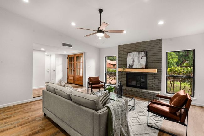 Living room with ceiling fan, recessed lighting, a brick fireplace, baseboards, and vaulted ceiling | Image 6