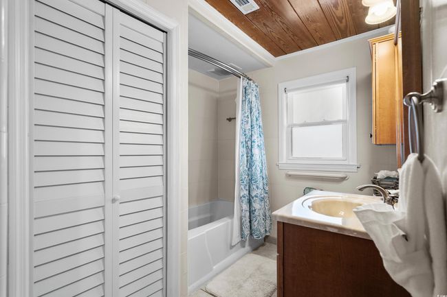 Bathroom with wooden ceiling, shower / bath combo, vanity, a closet, and tile patterned flooring | Image 36