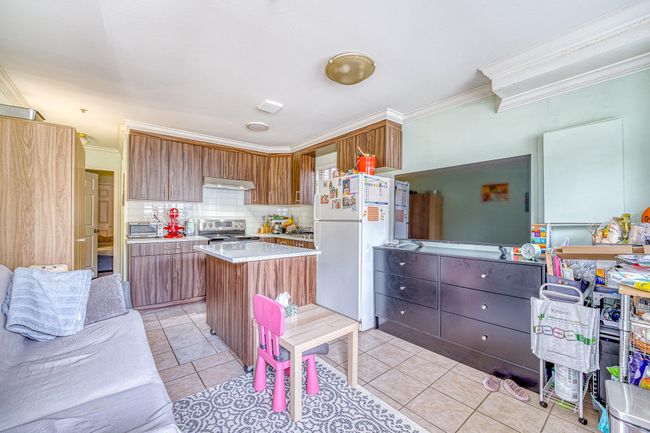 Kitchen with stainless steel range with electric cooktop, freestanding refrigerator, crown molding, decorative backsplash, and a center island | Image 23