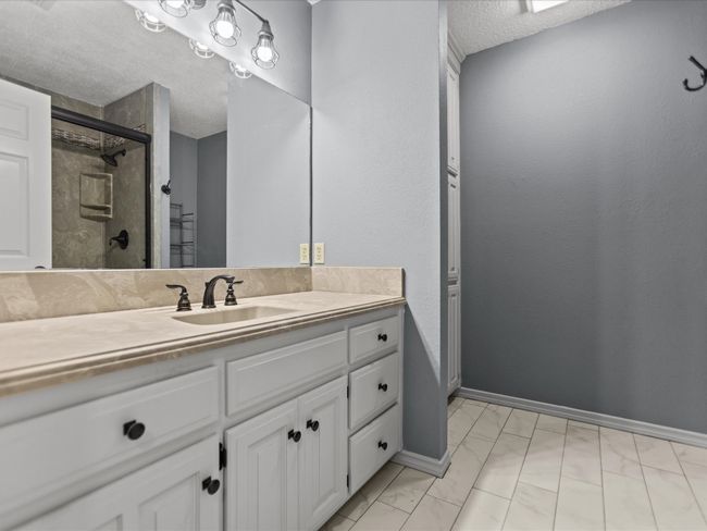 Bathroom 2 featuring a textured ceiling, marble finish floors, an enclosed shower, and vanity | Image 31
