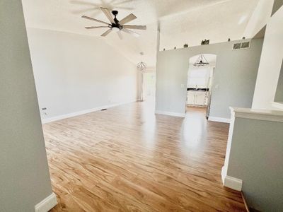 Unfurnished living room featuring lofted ceiling, ceiling fan, sink, light hardwood / wood-style floors, and a textured ceiling | Image 3