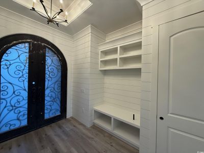 Foyer entrance with hardwood / wood-style floors, wood walls, french doors, and an inviting chandelier | Image 2