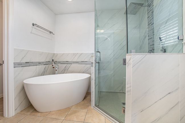 Full bathroom with a marble finish shower, tile walls, tile patterned floors, and a freestanding​​‌​​​​‌​​‌‌​‌‌​​​‌‌​​‌‌​‌​​​​​‌ bath | Image 22