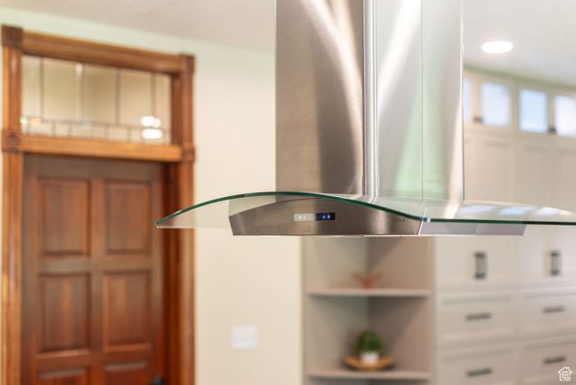 Kitchen view of island exhaust hood and white cabinets | Image 10