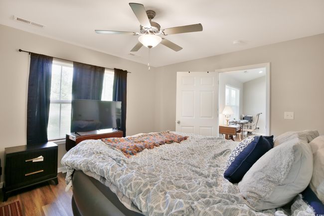 Bedroom with wood finished floors, ceiling fan, and an office area | Image 18