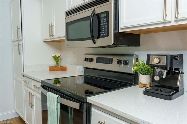Kitchen featuring stainless steel appliances, white cabinetry, and light stone countertops | Image 8