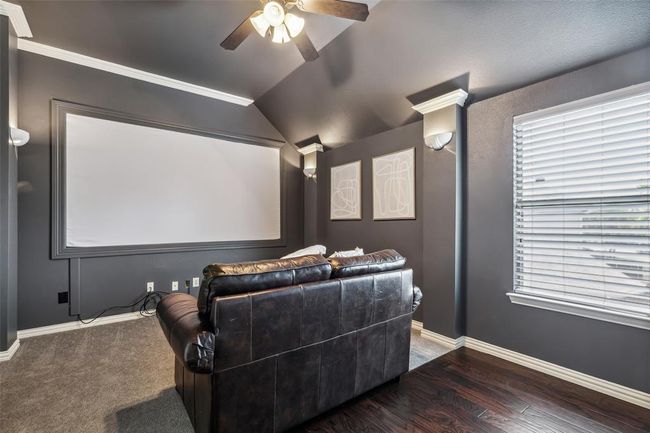 Home theater room with vaulted ceiling, ceiling fan, carpet flooring, and crown molding | Image 21