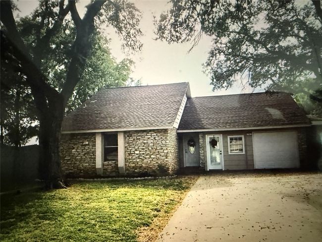 View of front of home with a garage, driveway, stone siding, and a shingled roof | Image 26