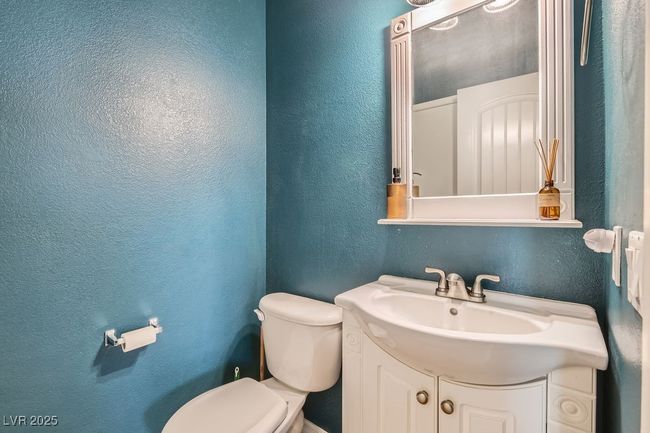 Bathroom featuring toilet, vanity, and a textured wall | Image 13