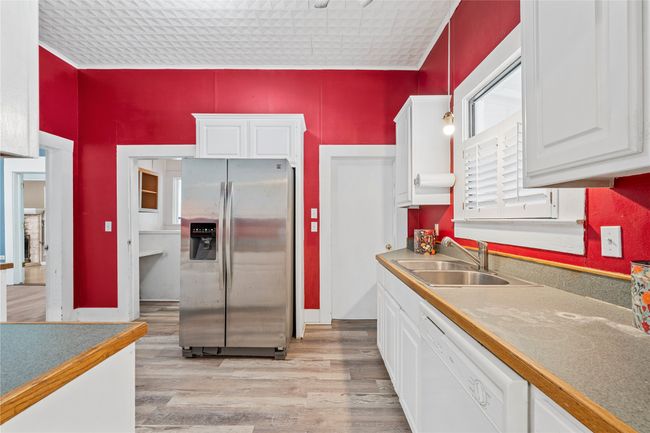 Kitchen with stainless steel fridge with ice dispenser, dishwasher, and white cabinets | Image 15