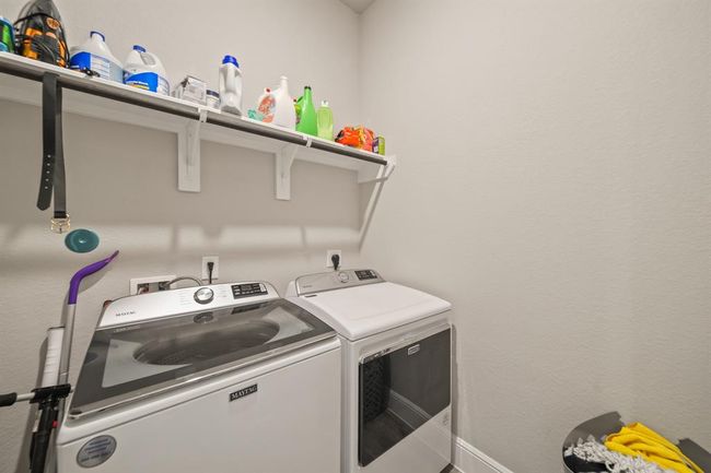Functional laundry room with shelf storage and newer washer/dryer units on the 1st floor. | Image 39