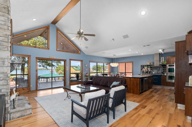 Living room featuring sink, high vaulted ceiling, ceiling fan, light hardwood / wood-style flooring, and beam ceiling | Image 4
