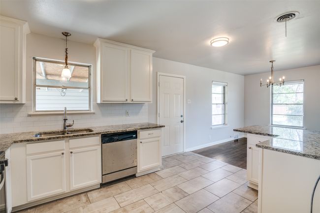 Kitchen featuring stainless steel appliances, an inviting chandelier, a sink, and decorative backsplash | Image 15