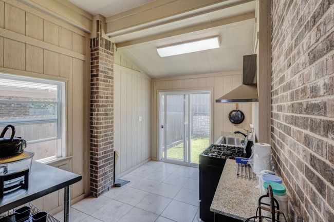 Kitchen with lofted ceiling, gas stove, light tile patterned floors, a sink, and wall chimney exhaust hood | Image 30