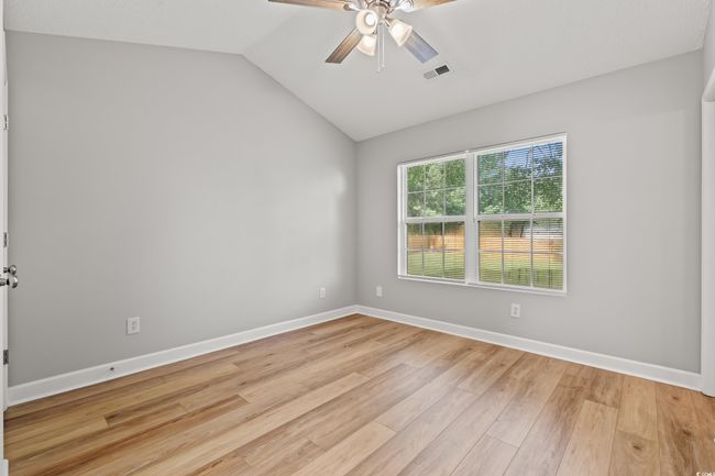Unfurnished room featuring light wood finished floors, a ceiling fan, and vaulted ceiling | Image 15