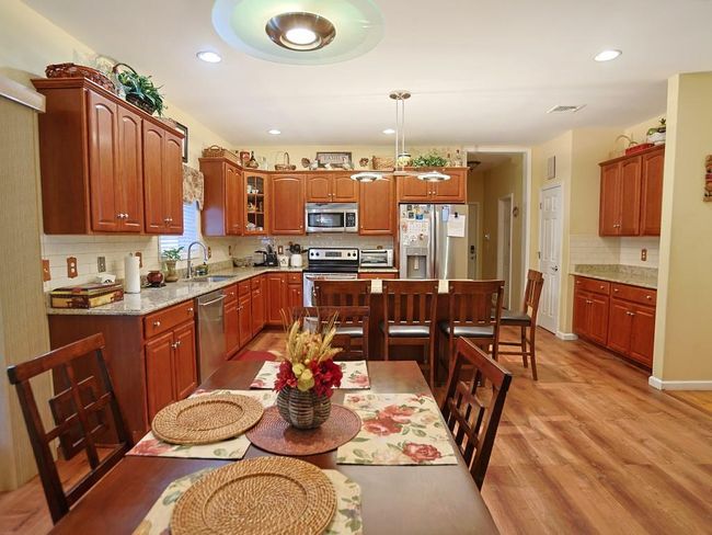 Kitchen with a sink, light wood finished floors, visible vents, appliances with stainless steel finishes, and glass insert cabinets | Image 7