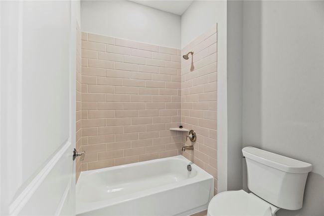The secondary bathroom includes a sleek tub/shower combo with modern tile surround and brushed nickel fixtures offering both style and functionality for guests or family members. | Image 26