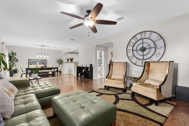 Living room featuring wood finished floors, ceiling fan, arched walkways, and a chandelier | Image 6
