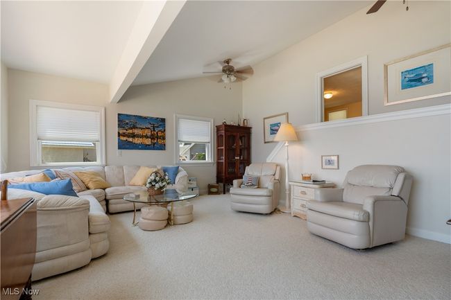 Carpeted living room featuring a ceiling fan and vaulted ceiling | Image 8