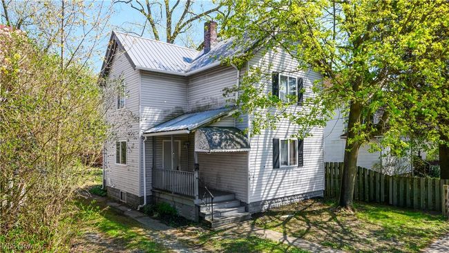 Traditional-style house featuring a chimney, fence, and metal roof | Image 17