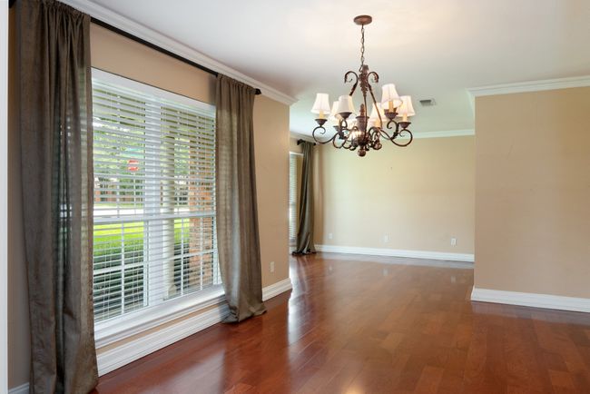 Empty room with a chandelier, wood finished floors, and ornamental molding | Image 8