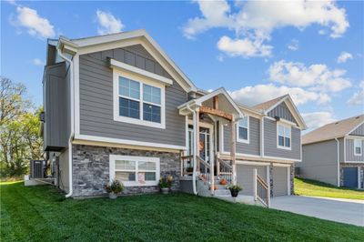 Raised ranch featuring cooling unit, a front lawn, and a garage | Image 2