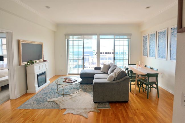 Living room featuring plenty of natural light, light wood-style floors, a glass covered fireplace, and crown molding | Image 32