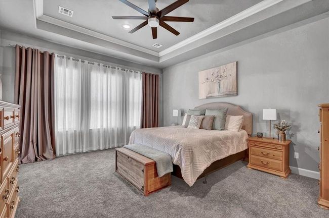 Bedroom with a tray ceiling, ornamental molding, carpet, baseboards, and ceiling fan | Image 27