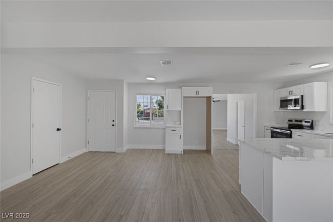 Kitchen featuring appliances with stainless steel finishes, light wood finished floors, white cabinetry, and light stone countertops | Image 15