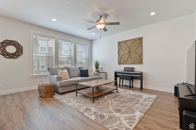 Living area with a ceiling fan, light wood-type flooring, recessed lighting, and a textured ceiling | Image 6