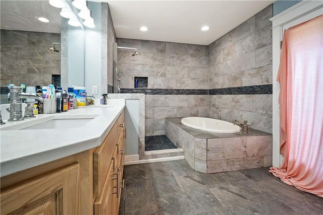 Bathroom with a bath, a sink, tile walls, and a walk in shower | Image 18