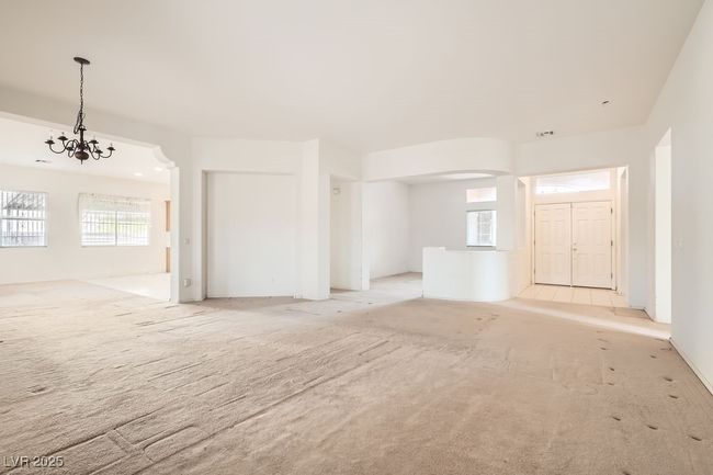Spare room featuring light carpet, arched walkways, and a chandelier | Image 5