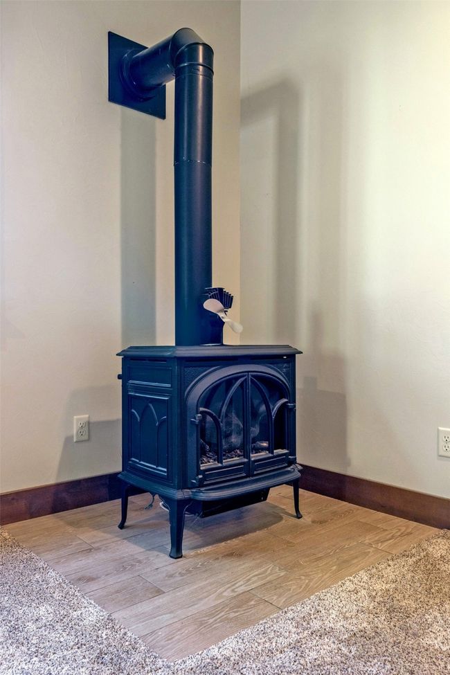 Detailed view of a wood stove, wood finished floors, and baseboards | Image 34