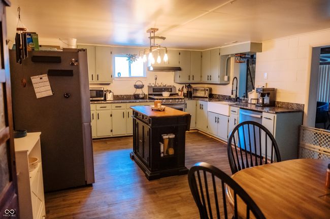kitchen featuring dark countertops, a center island, appliances with stainless steel finishes, and dark wood-type flooring | Image 23