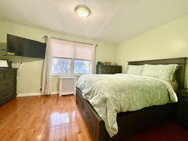Bedroom with radiator heating unit, wood-type flooring, and baseboards | Image 6