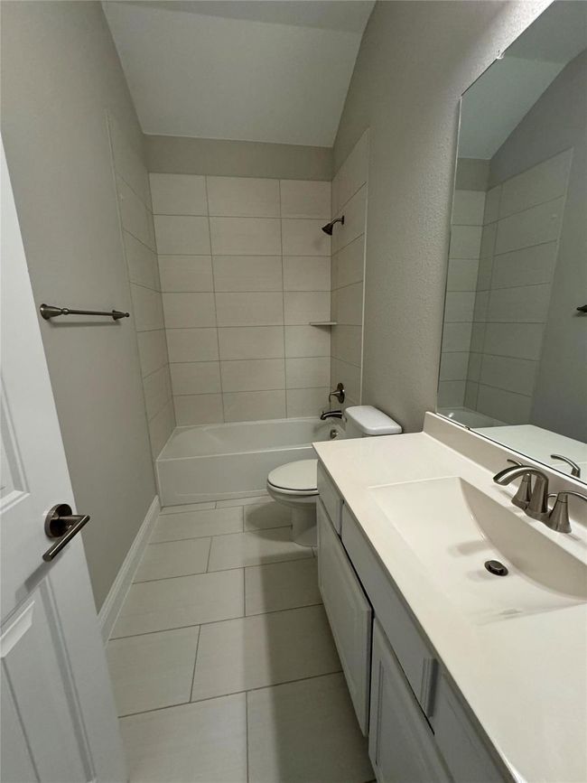 Full bathroom featuring vanity, tile patterned flooring, bathtub / shower combination, and lofted ceiling | Image 39