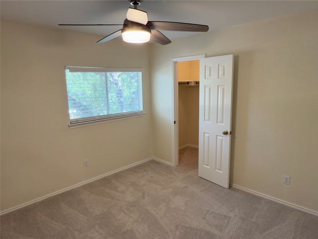 Unfurnished bedroom featuring a walk in closet, light carpet, and a ceiling fan | Image 27