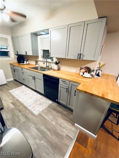 Kitchen featuring black dishwasher, dark hardwood / wood-style floors, sink, ceiling fan, and butcher block countertops | Image 3