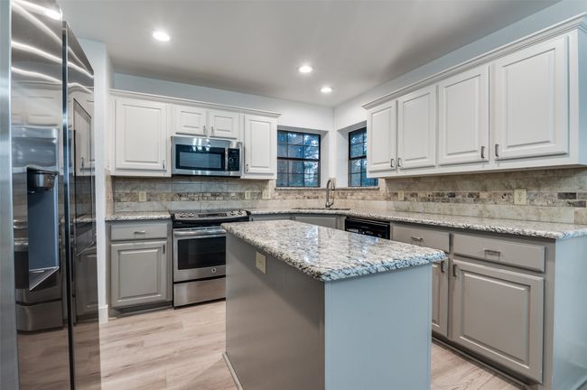 Kitchen featuring stainless steel appliances, gray cabinetry, decorative backsplash, a kitchen island, and recessed lighting | Image 11