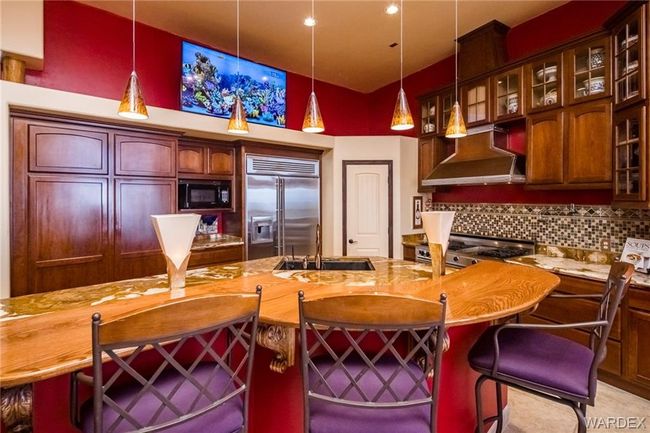 Kitchen featuring built in appliances, wall chimney exhaust hood, tasteful backsplash, and decorative light fixtures | Image 35