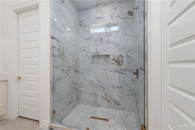 Luxurious Walk-In ShowerStunning walk-in shower with marble walls, custom niche, rainfall showerhead, and gold accents for a refined touch. | Image 19