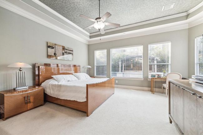 The oversized Primary Retreat measures 18x16 & features upgraded carpet, a tray ceiling with faux painting, crown molding & SIX windows. | Image 16