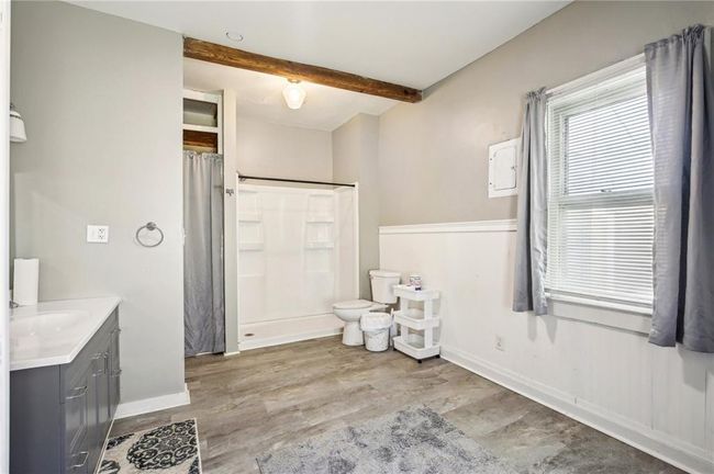 Full bath featuring toilet, beamed ceiling, wood finished floors, a shower with shower curtain, and vanity | Image 19