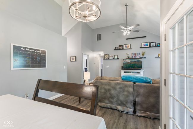 dining room with wood finished floors, a chandelier, a ceiling fan, and high vaulted ceiling | Image 8