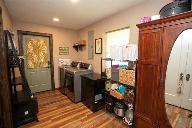 Laundry room featuring washer and dryer, wood finished floors, recessed lighting, and electric panel | Image 39