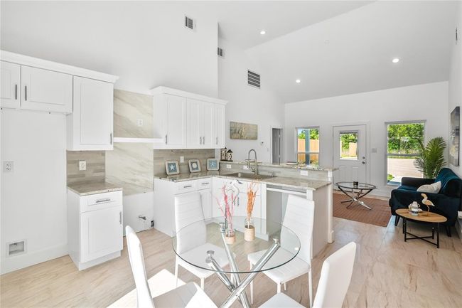 Bright and inviting kitchen with sleek white cabinetry and modern finishes, perfect for culinary creativity and entertaining. | Image 11