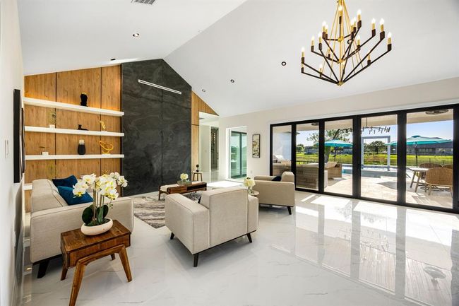 Bathed in natural light, this stunning living area features soaring ceilings, a dramatic feature wall, and expansive sliding glass doors that offer seamless indoor-outdoor living and breathtaking views of the backyard oasis. | Image 38