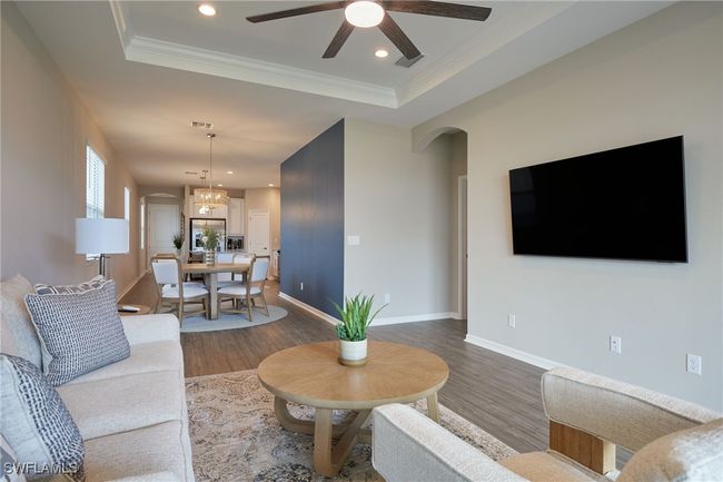 Living area with arched walkways, a tray ceiling, and wood finished floors | Image 6